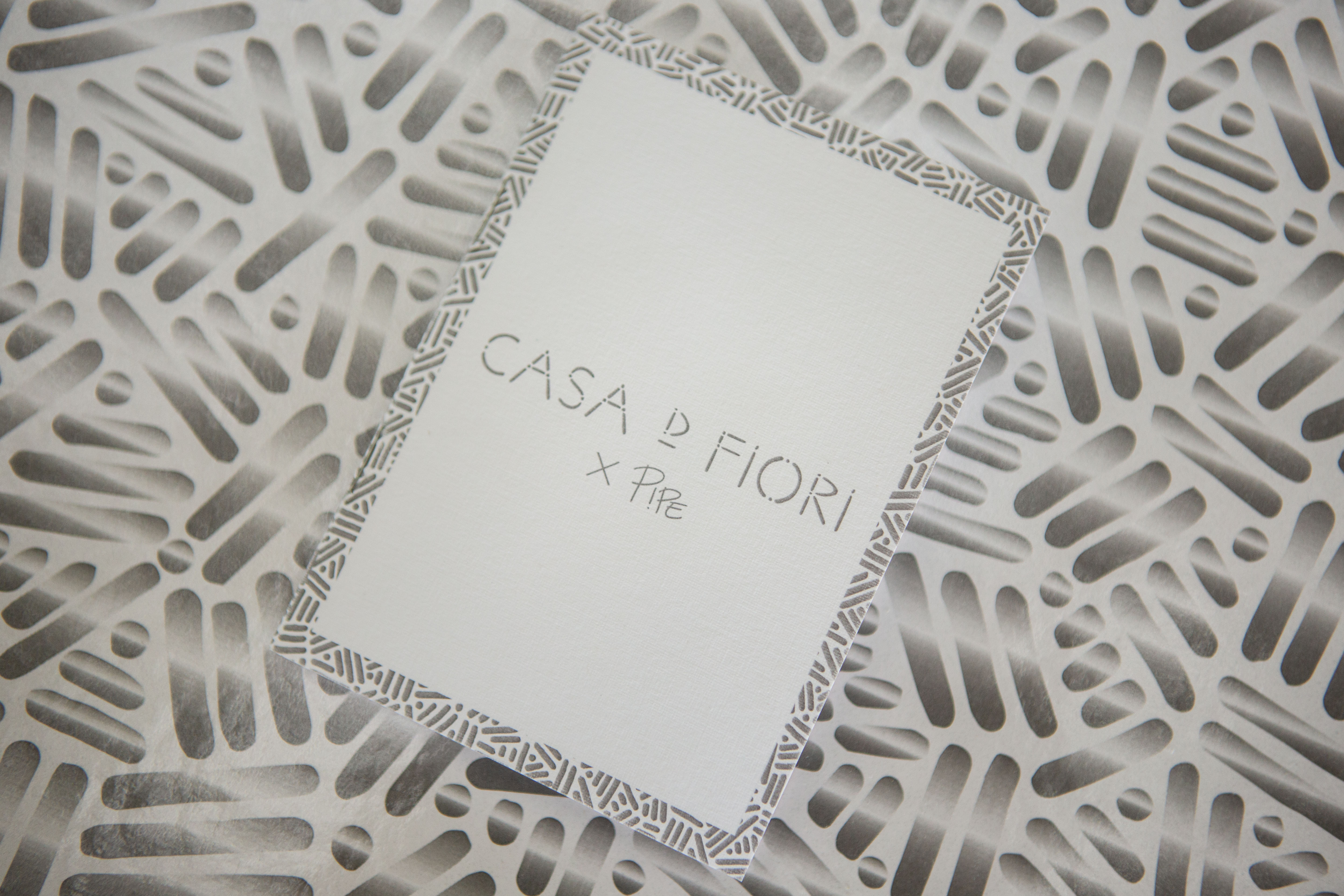 Limited-edition Casa D Fiori floral presentation box featuring Pipe Yanguas's intricate white and gray dots-and-lines artwork, photographed on a wooden table.