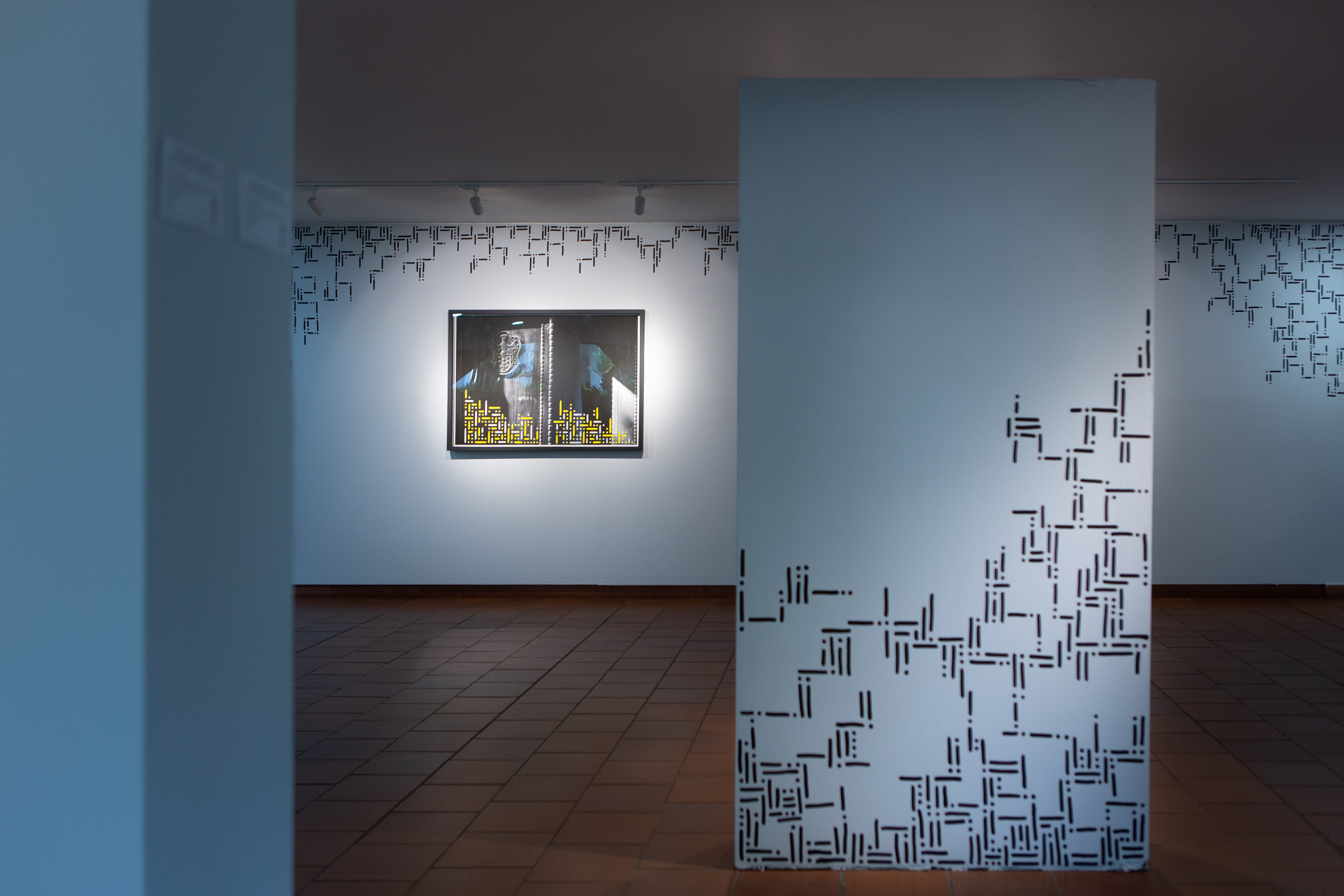 Installation view of Pipe Yanguas’s photographic works at Club Campestre de Cali during a 2021 group exhibition, featuring framed photographs and a gallery partition decorated with black dots-and-lines patterns.