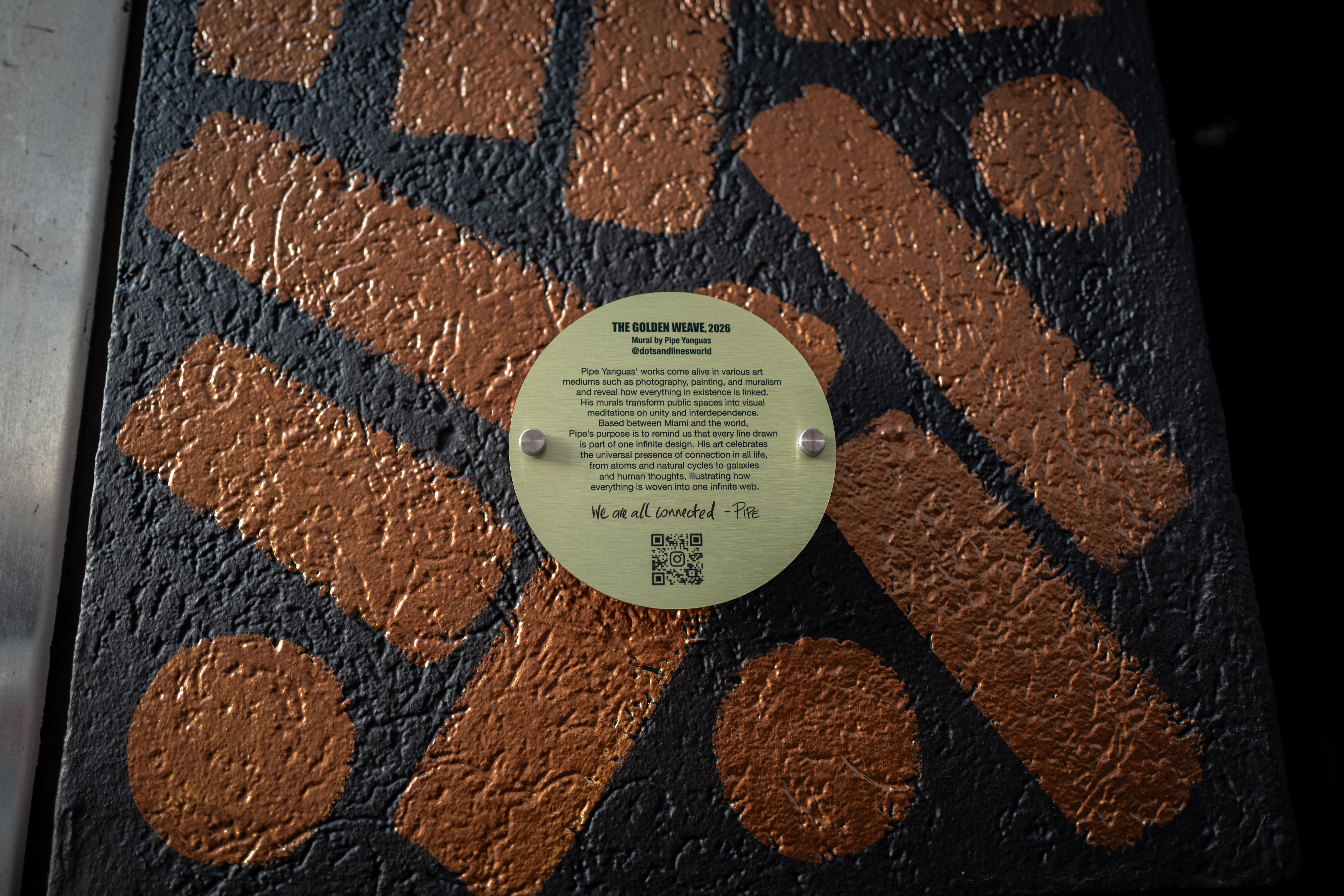 The Golden Weave: Round project plaque attached to a dark wall painted with golden dots and lines.