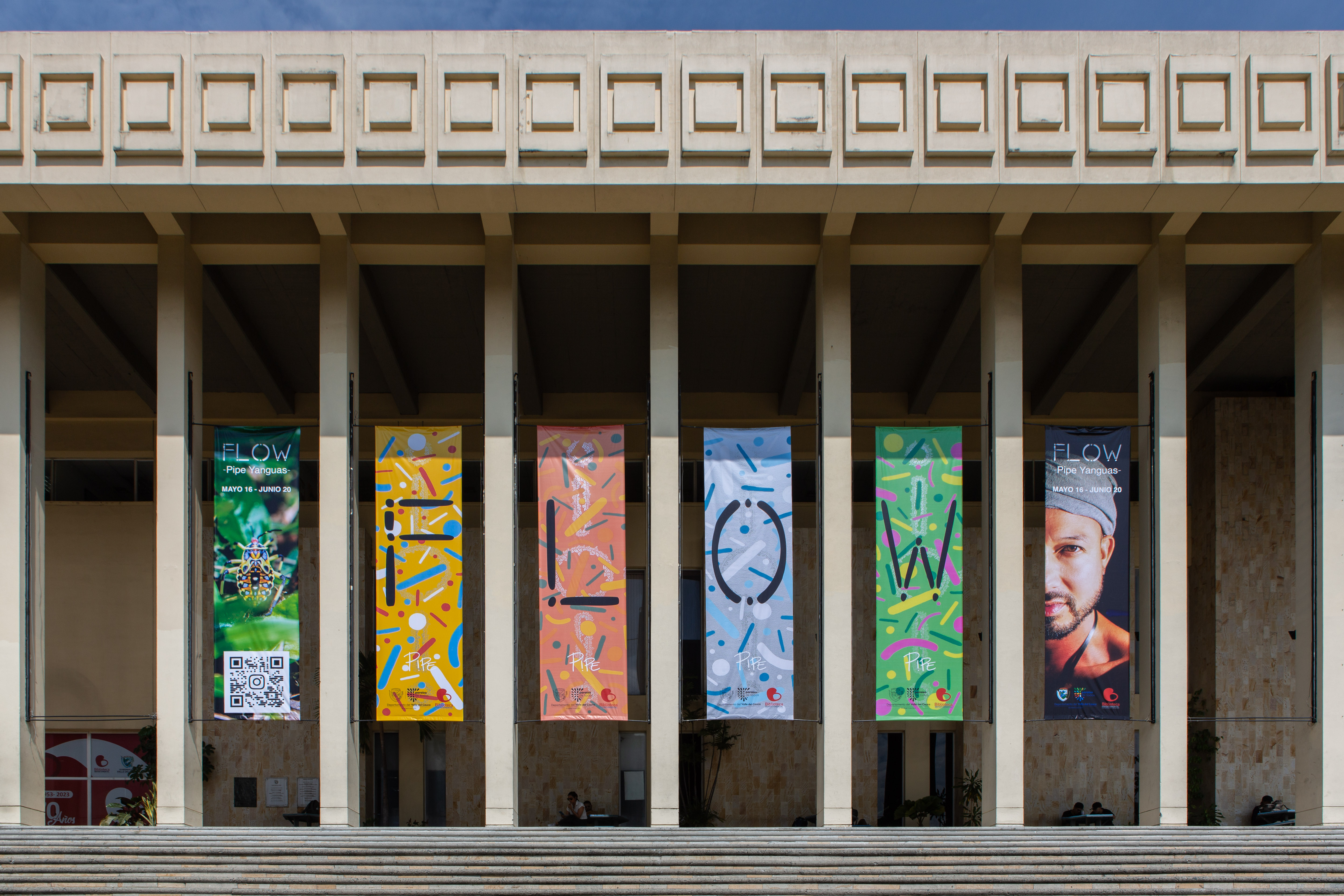 Exterior of DOMO Museo at the Biblioteca Departamental Jorge Garcés Borrero in Cali, Colombia, featuring colorful banners for Pipe Yanguas’s 2024 solo exhibition “FLOW.”