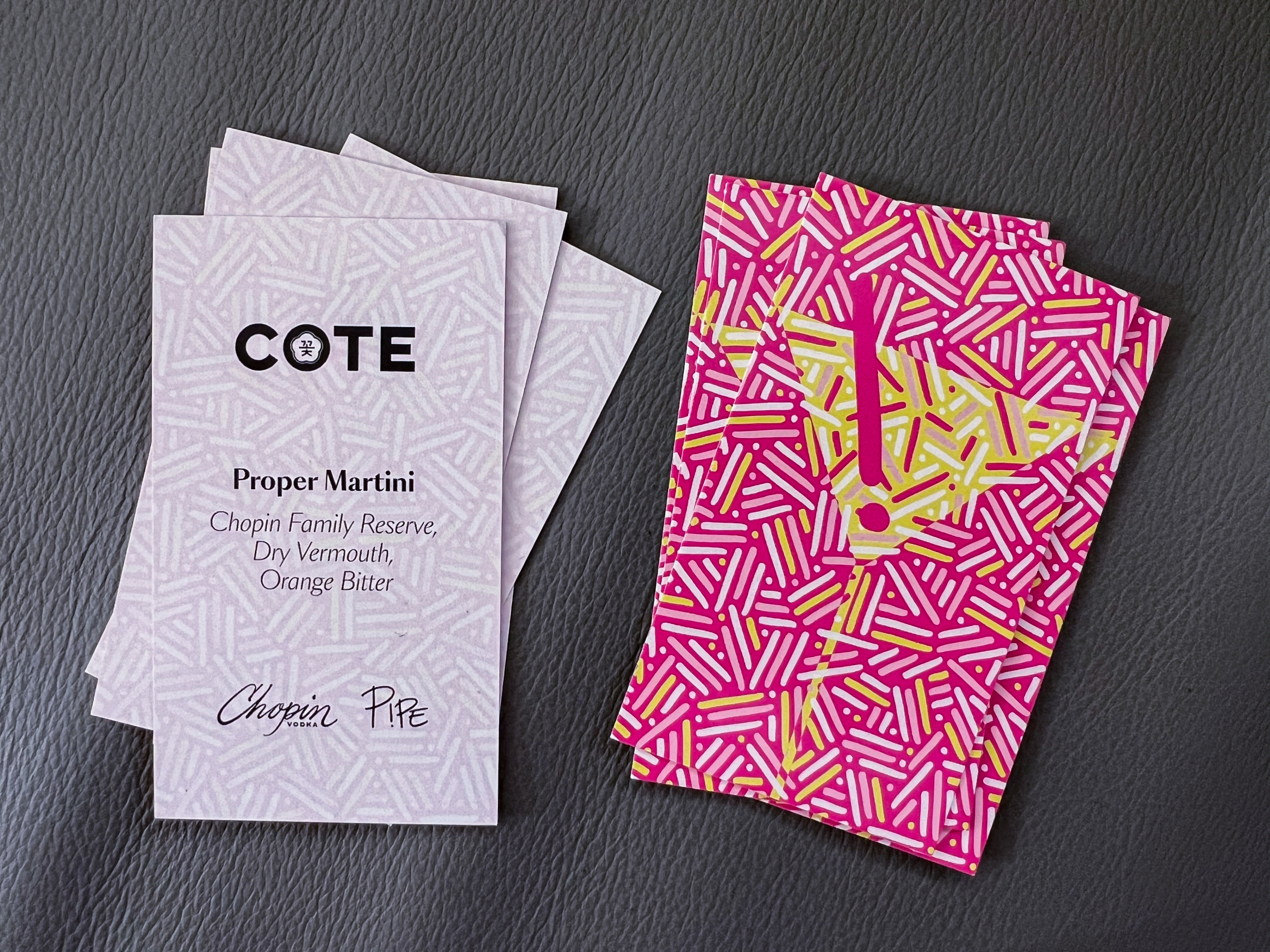 Collectible Proper Martini cocktail cards created for COTE Miami's ART AFTER DARK collaboration with Pipe Yanguas and Chopin Vodka, showing the cocktail information and vibrant pink-and-yellow dots-and-lines artwork.